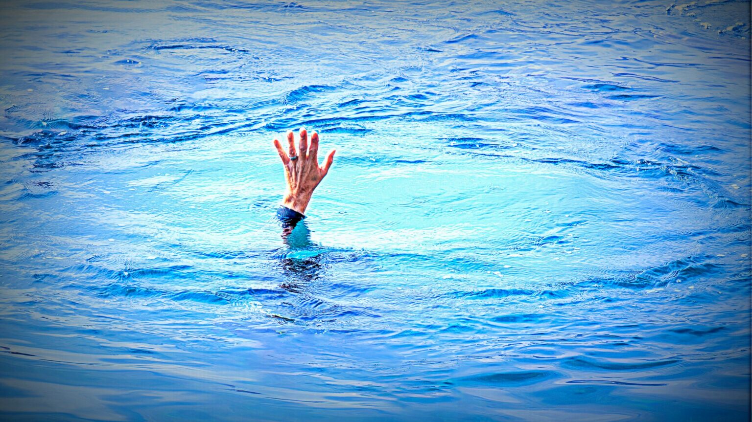 Eine Hand ragt aus einer Wasseroberfläche eines Sees oder Flusses