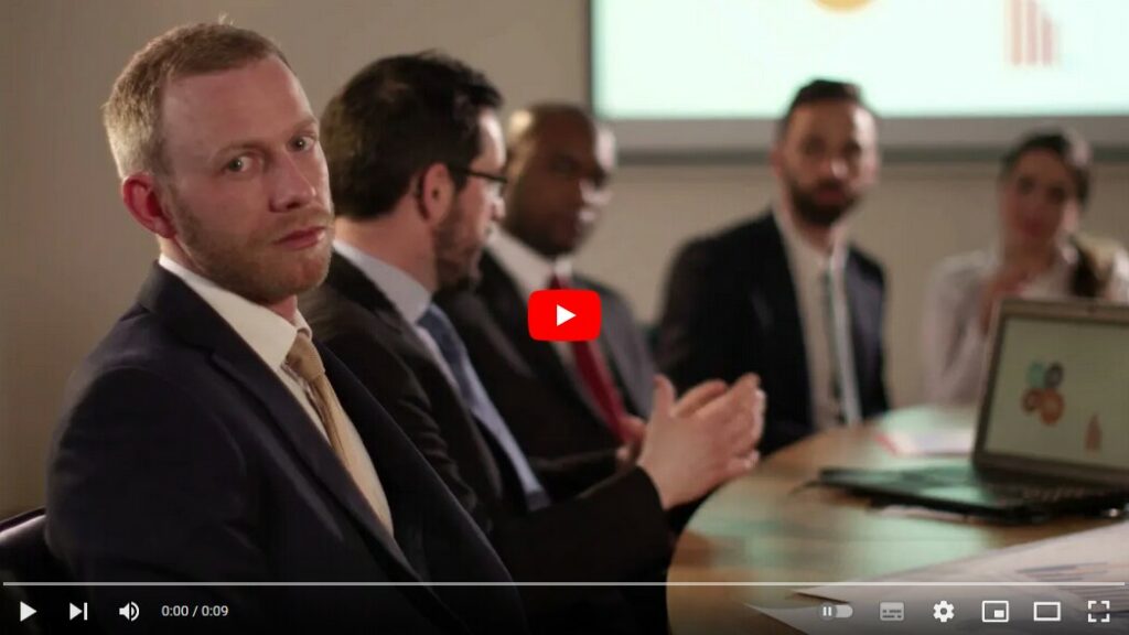 Video-Szene (Screenshot): Mann in einem Meeting, wendet sich von diesem ab und schaut desillusioniert in Richtung Betrachtende.
